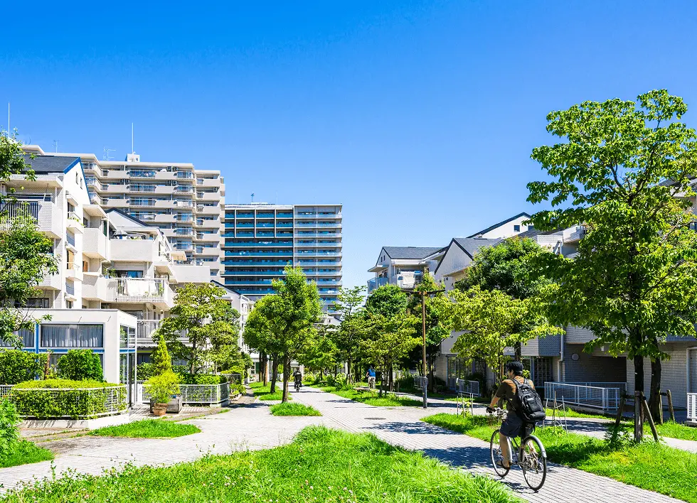 緑豊かな住宅街の風景。低層住宅とマンションが立ち並び、自然と共存する街づくりや住環境の良さを表した写真。