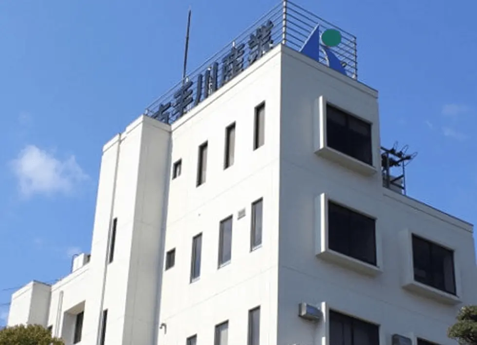 青空の下に建つ白い社屋の外観写真。企業の本社または事業拠点をイメージした建物外観。