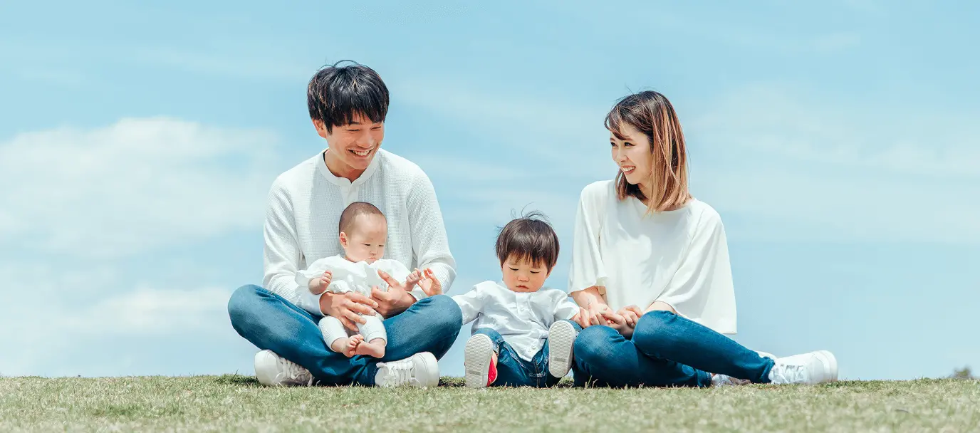 芝生の上で子どもと過ごす笑顔の家族