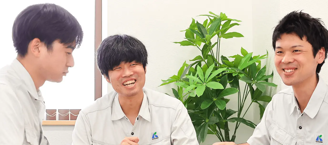 カフェスペースで談笑するスーツ姿の男女4人。コーヒーを手に笑顔で会話する、明るくリラックスした社内コミュニケーションの様子。