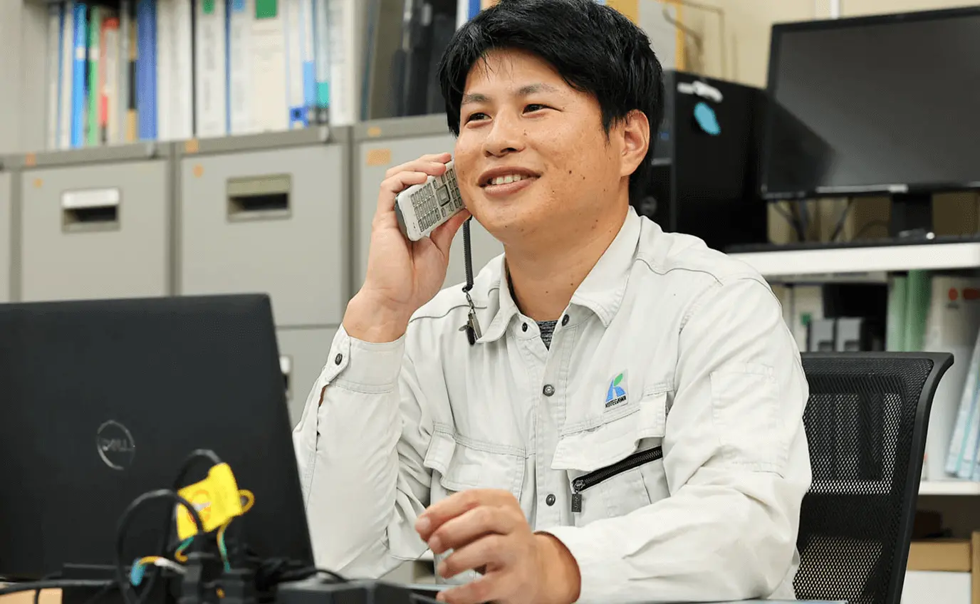 オフィスで電話対応をしながら業務を行う社員の様子