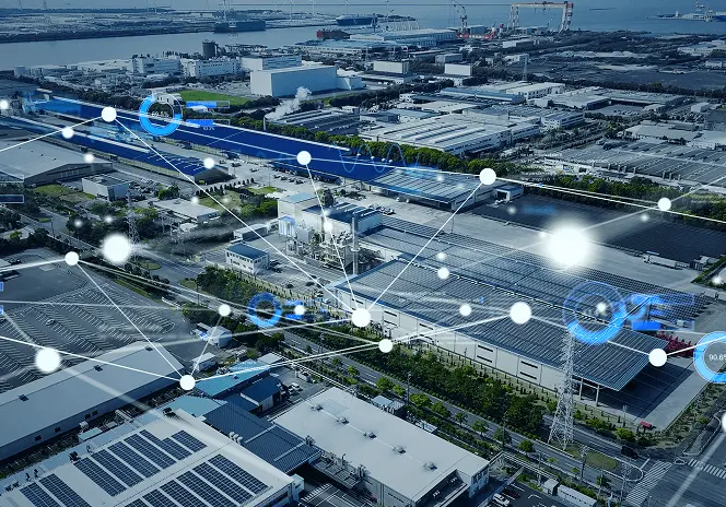 工場地帯を上空から撮影した風景に、ネットワーク接続を示すデジタルのラインやアイコンが重ねられ、スマートファクトリーやデジタル連携をイメージする構図。