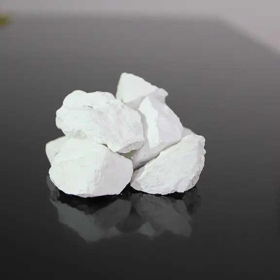 黒い台の上に、白く乾いた岩石の破片がいくつか積まれている様子。地盤改良材や鉱石サンプルのような白色の石素材を示すイメージ。