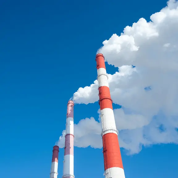 煙突から白い煙が上がる工場の写真。石灰が排ガス中の有害物質を吸着・中和する用途に使われることを表すイメージ。