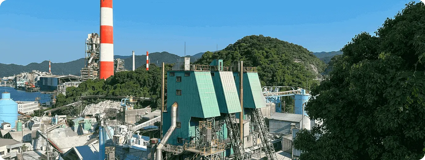 広大な工場設備と緑豊かな山々、海沿いの煙突群が広がる風景