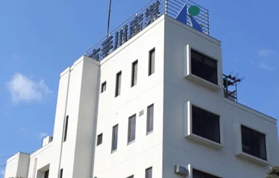 青空の下に立つ古手川産業の本社ビル外観